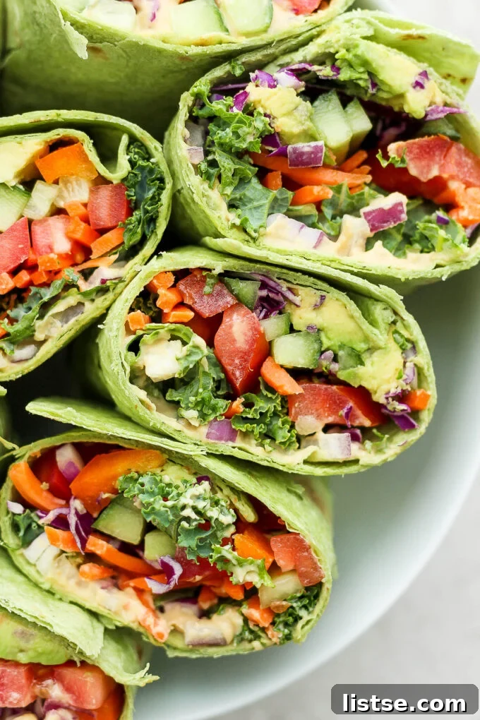 A close-up shot of a perfectly rolled vegan wrap, revealing its colorful and fresh ingredients, including hummus and a variety of vegetables.