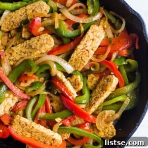 Easy Tempeh Fajitas - A vibrant platter of vegan tempeh fajitas with bell peppers, onions, and lime wedges, perfect for a healthy plant-based meal.