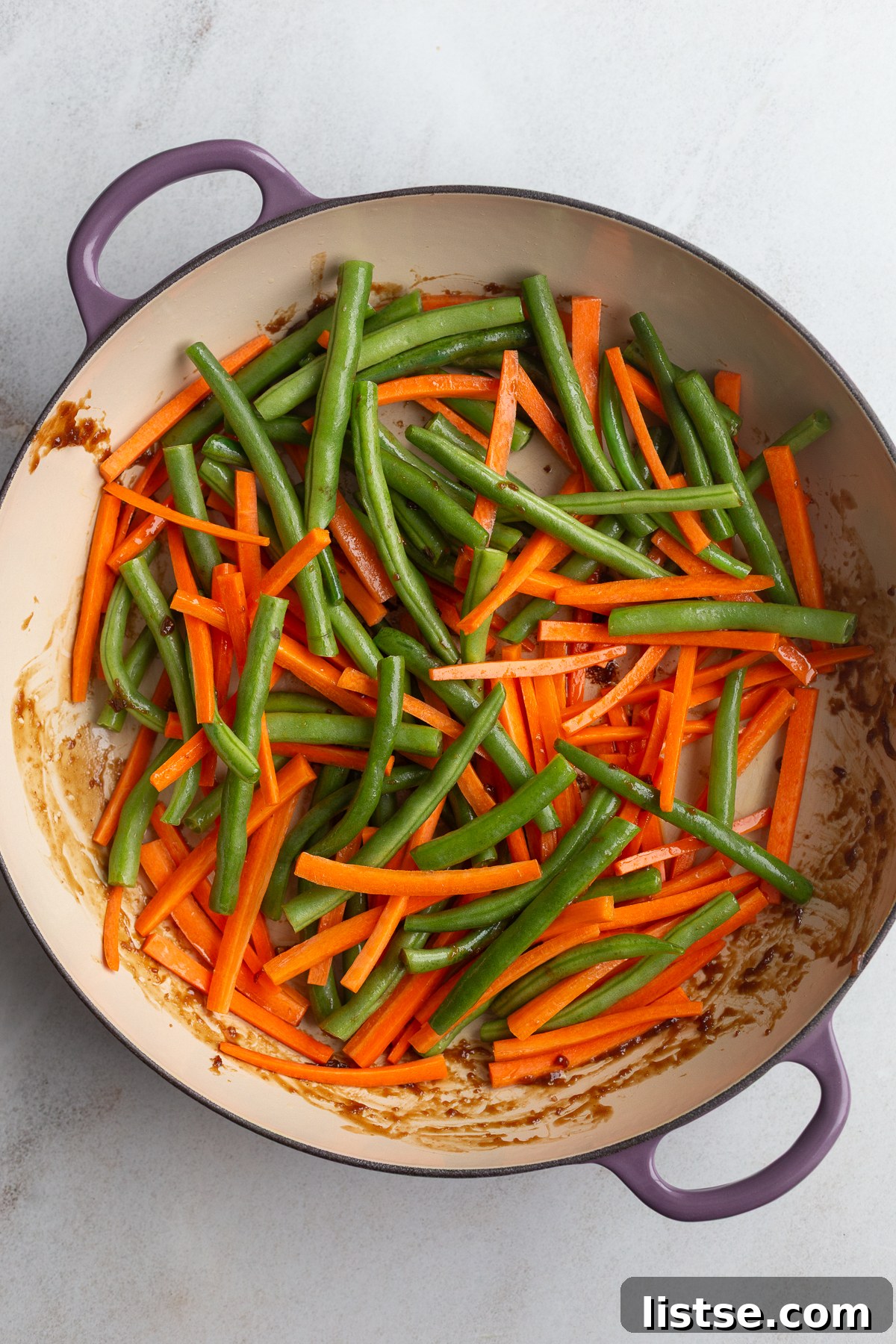 raw carrots and green beans in a large skillet