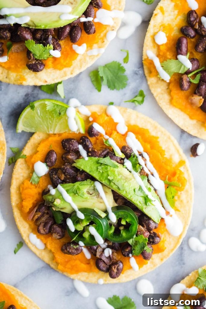 Vibrant Sweet Potato and Black Bean Tostadas 5 Four sweet potato and black bean tostadas presented on a wooden board with fresh garnishes