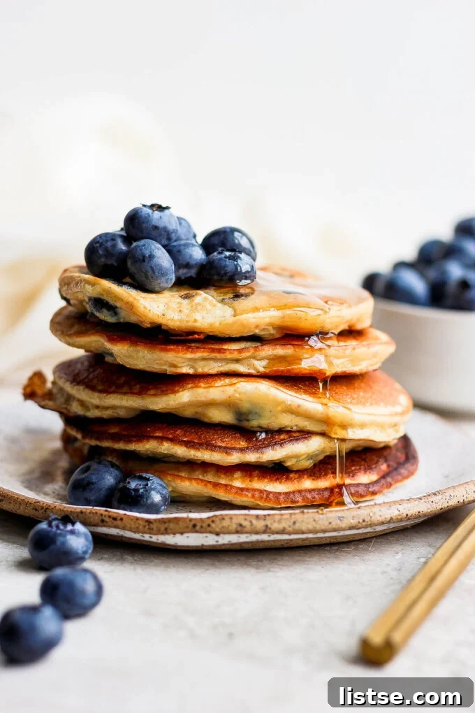 Power-Packed Banana Protein Pancakes 2 Stack of fluffy banana protein pancakes topped with blueberries and maple syrup, ready to be enjoyed.
