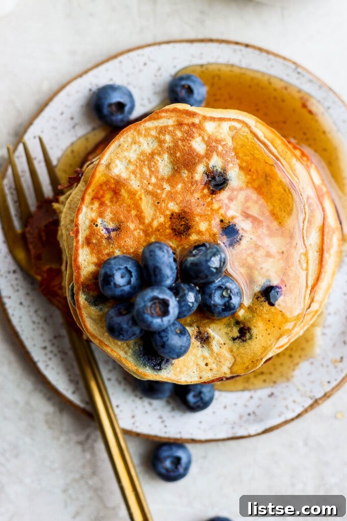Power-Packed Banana Protein Pancakes 3 Close-up of golden brown pancakes topped with vibrant fresh blueberries and a hint of syrup.