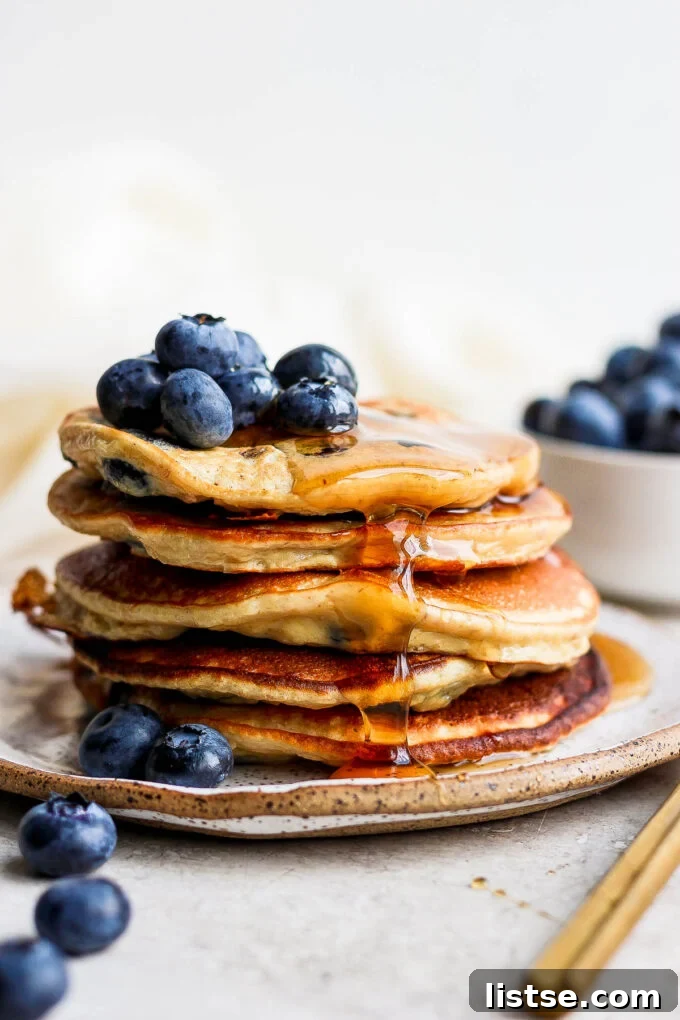 Power-Packed Banana Protein Pancakes 5 A beautiful stack of golden banana protein pancakes on a plate, generously drizzled with rich maple syrup.