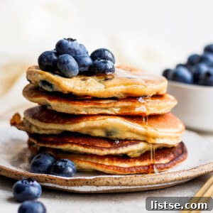Stack of banana protein pancakes topped with blueberries and syrup.