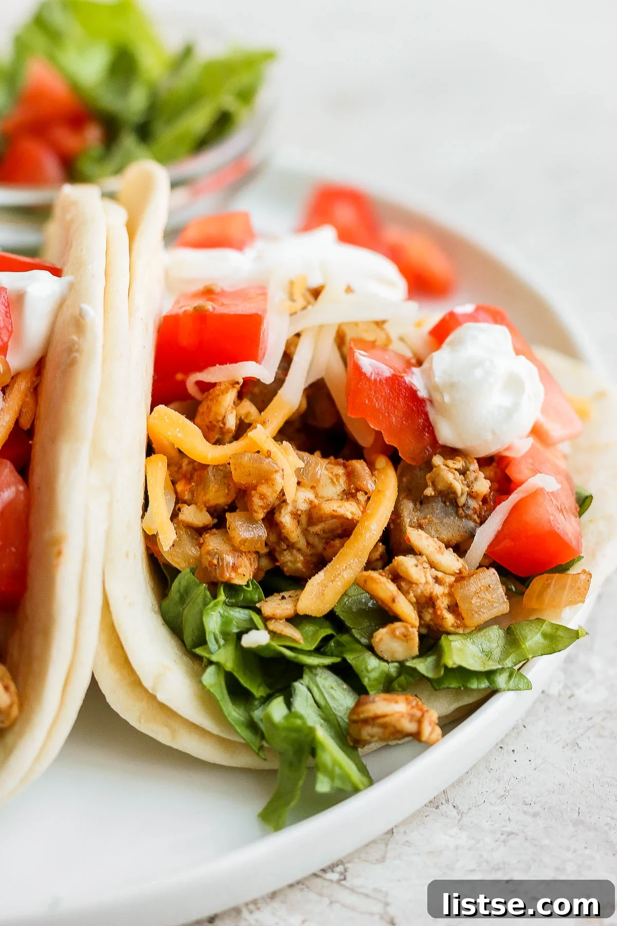 Delicious tempeh tacos on flour tortillas, garnished with cheese, fresh tomatoes, and vibrant cilantro