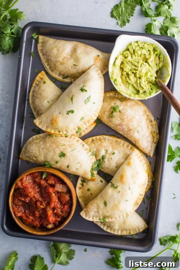 baked chicken empanadas, golden brown and perfectly crimped, arranged on a baking sheet