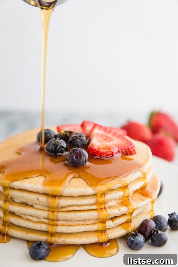 Perfectly Plant-Based Pancakes 2 Fluffy and golden easy vegan pancakes stacked high, drizzled with maple syrup and topped with fresh berries, ready for a delicious plant-based breakfast.