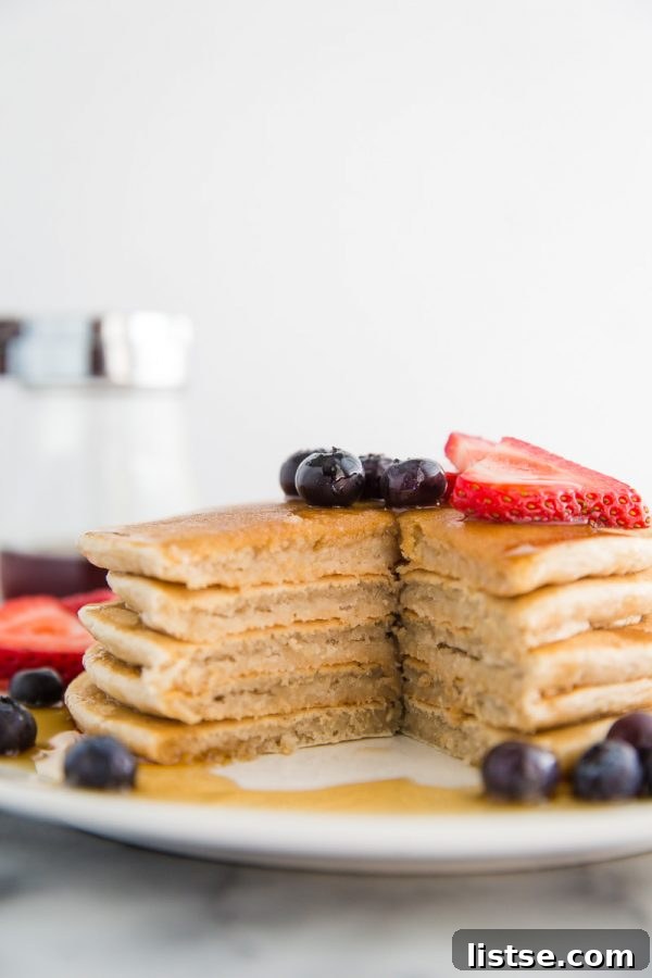 Perfectly Plant-Based Pancakes 3 Close-up of a stack of fluffy vegan banana pancakes, with a golden brown crust and soft interior, garnished with fresh fruit for a healthy and satisfying breakfast.