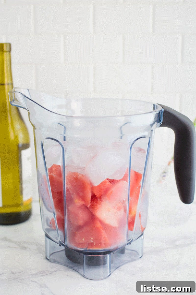 Pouring white wine into a blender with frozen watermelon for a slushie