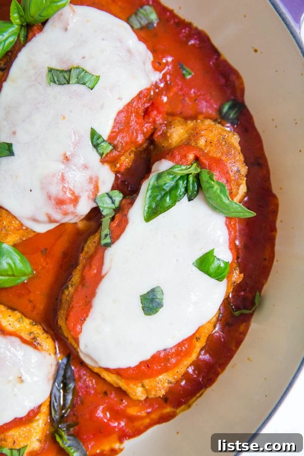 Keto Chicken Parmesan topped with marinara sauce and fresh mozzarella, ready for the oven.
