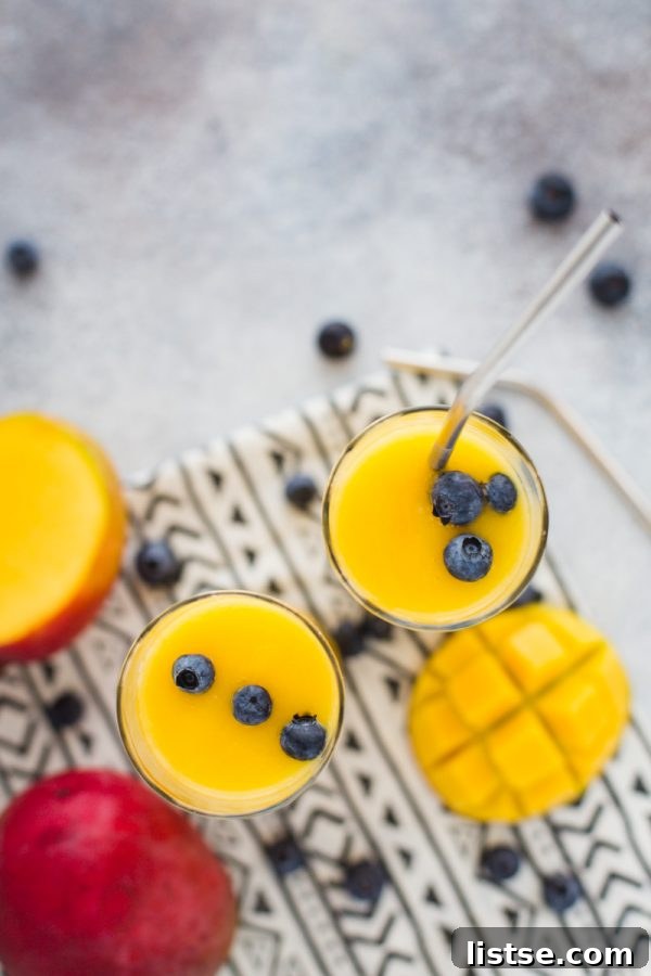 Mango Wine Slushie in a tall glass, garnished with a mango slice and mint, perfect for summer.