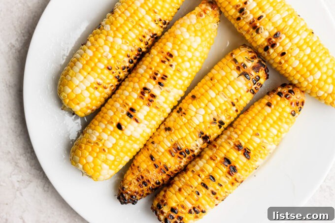 Charred corn on the cob being grilled, showing grill marks.