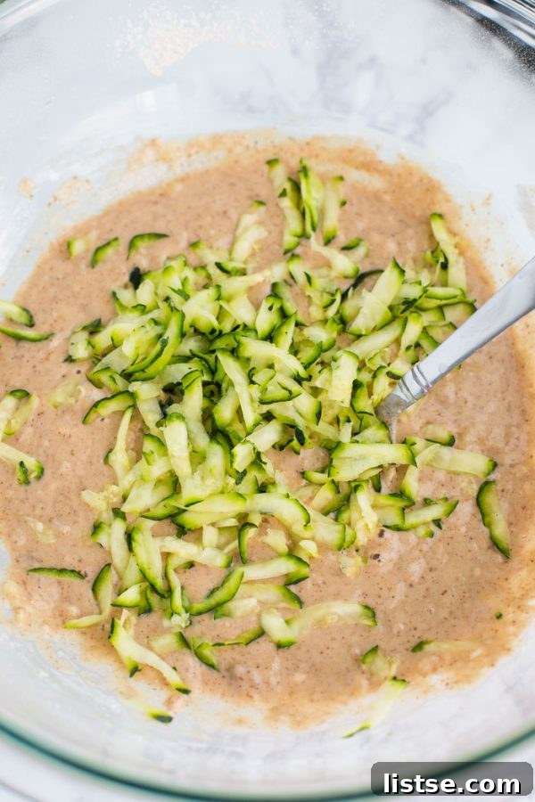 Squeezing excess moisture from grated zucchini for vegan muffins