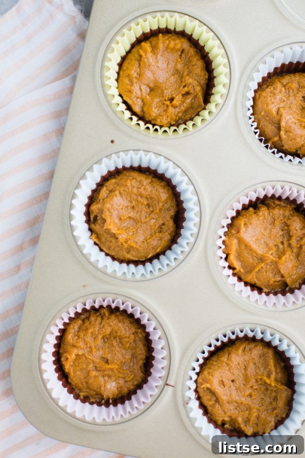 Assembling Pumpkin Peanut Butter Cups in muffin liners with melted chocolate