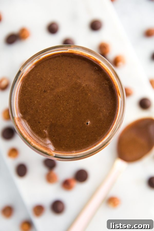 A jar of homemade Nutella with a spoon dipped in, showing its velvety smooth texture and rich color, ready to be enjoyed.