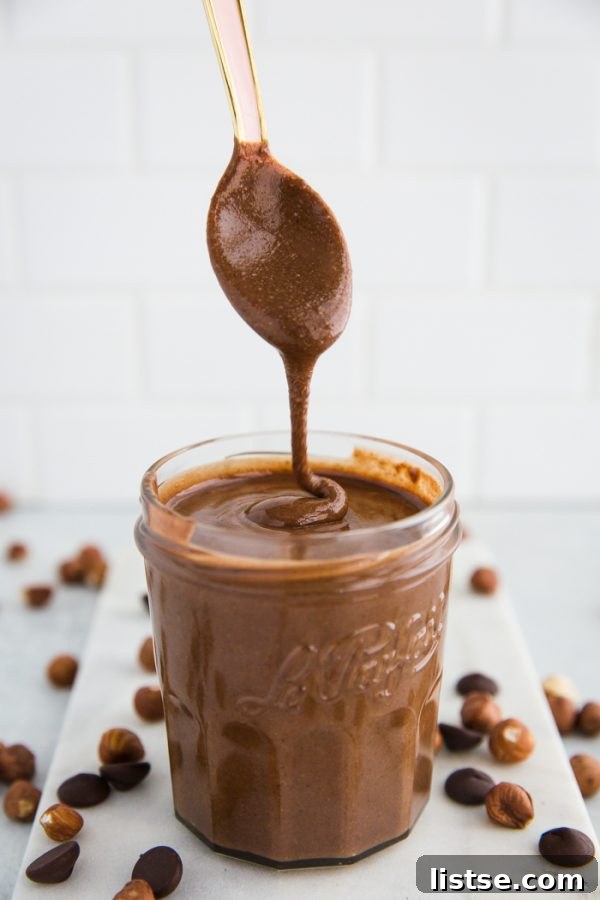 Blended hazelnut butter in a food processor, with melted dark chocolate and a pinch of salt being added, ready for final mixing.