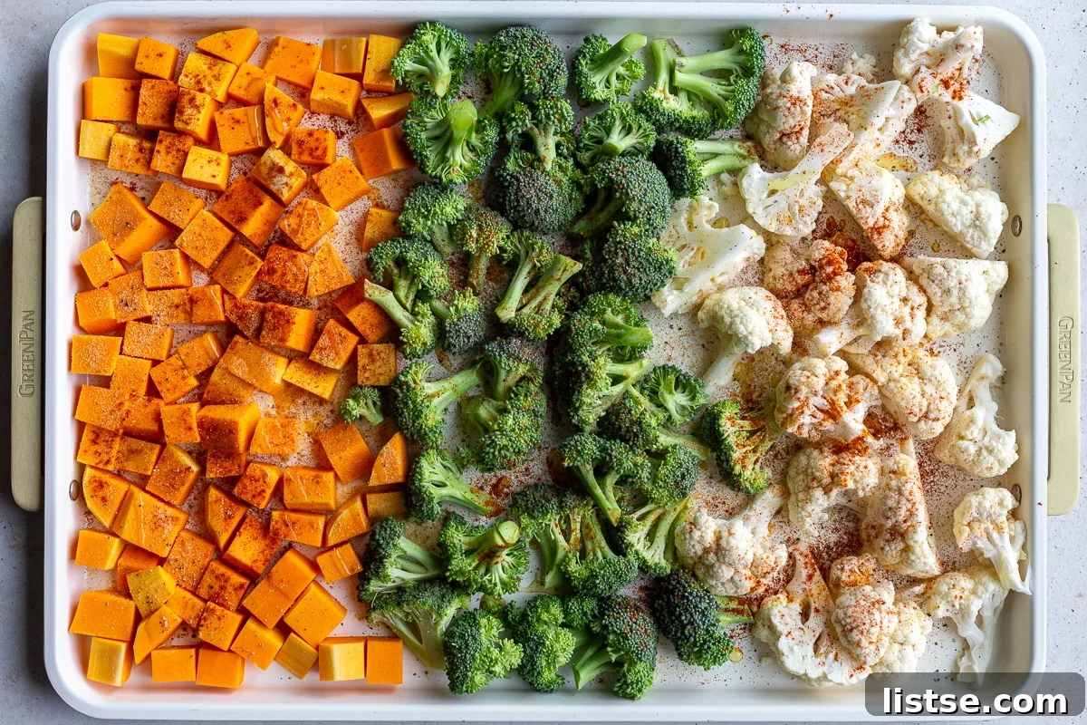 butternut squash, broccoli and cauliflower florets lined up on a baking tray and sprinkled with spices