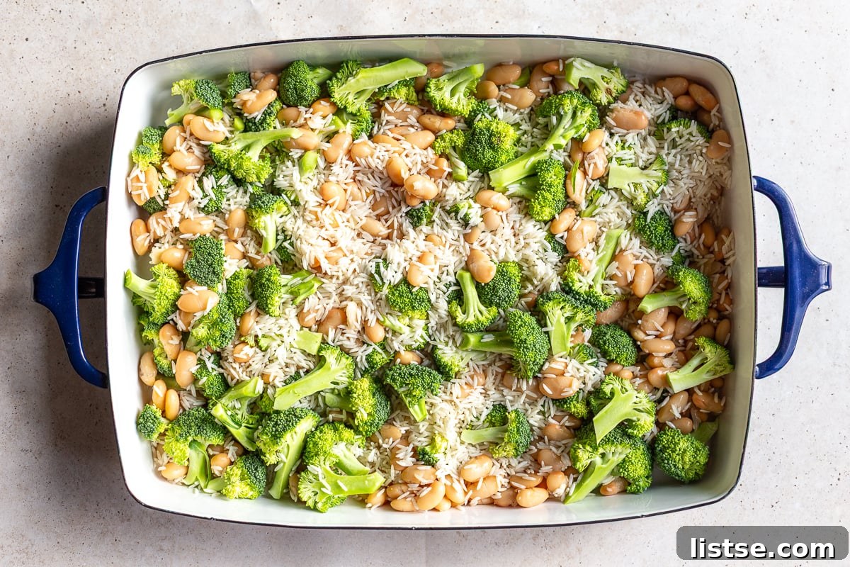 Uncooked rice, broccoli, and white beans spread in a casserole dish
