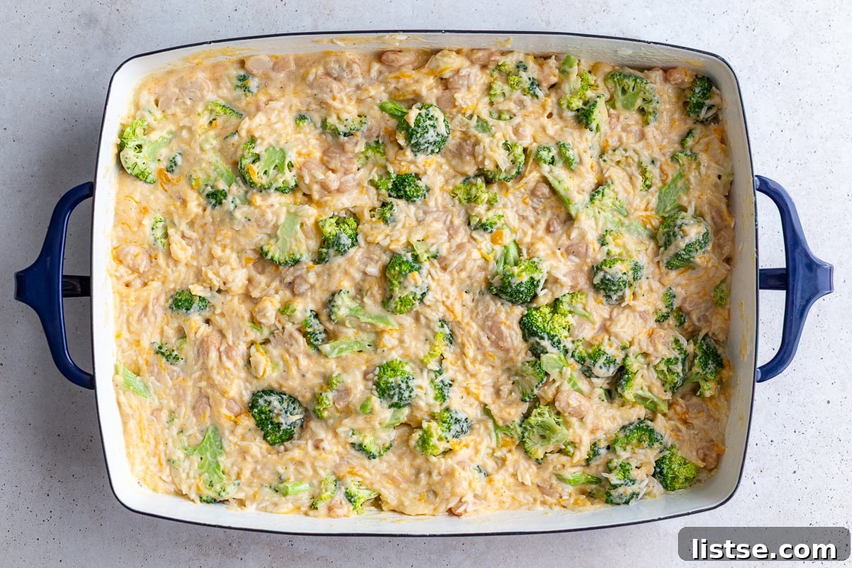 Pouring the creamy cheese sauce over the rice, broccoli, and beans mixture