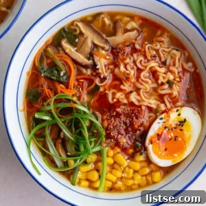 Easy homemade ramen in a large ramen bowl. The ramen is topped with a soft boiled egg, green onions, corn, and sesame seeds.