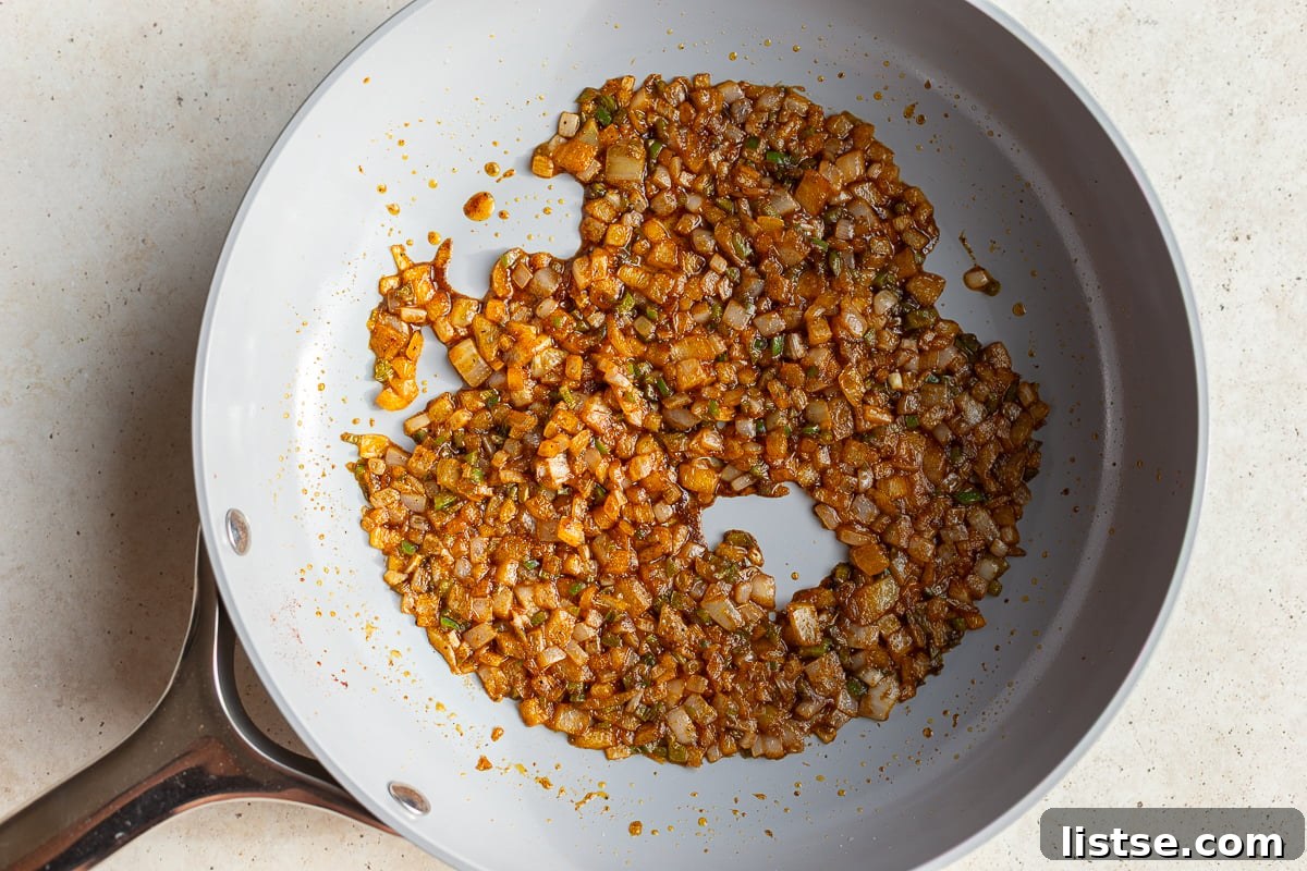 Finely minced onion, jalapeño, chili powder, paprika, and cumin sizzling in canola oil in a large skillet, building a fragrant aromatic base