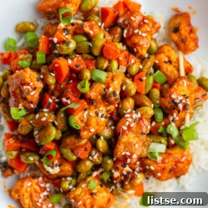 Gochujang tofu and edamame stir fry in a large white bowl topped with sesame seeds
