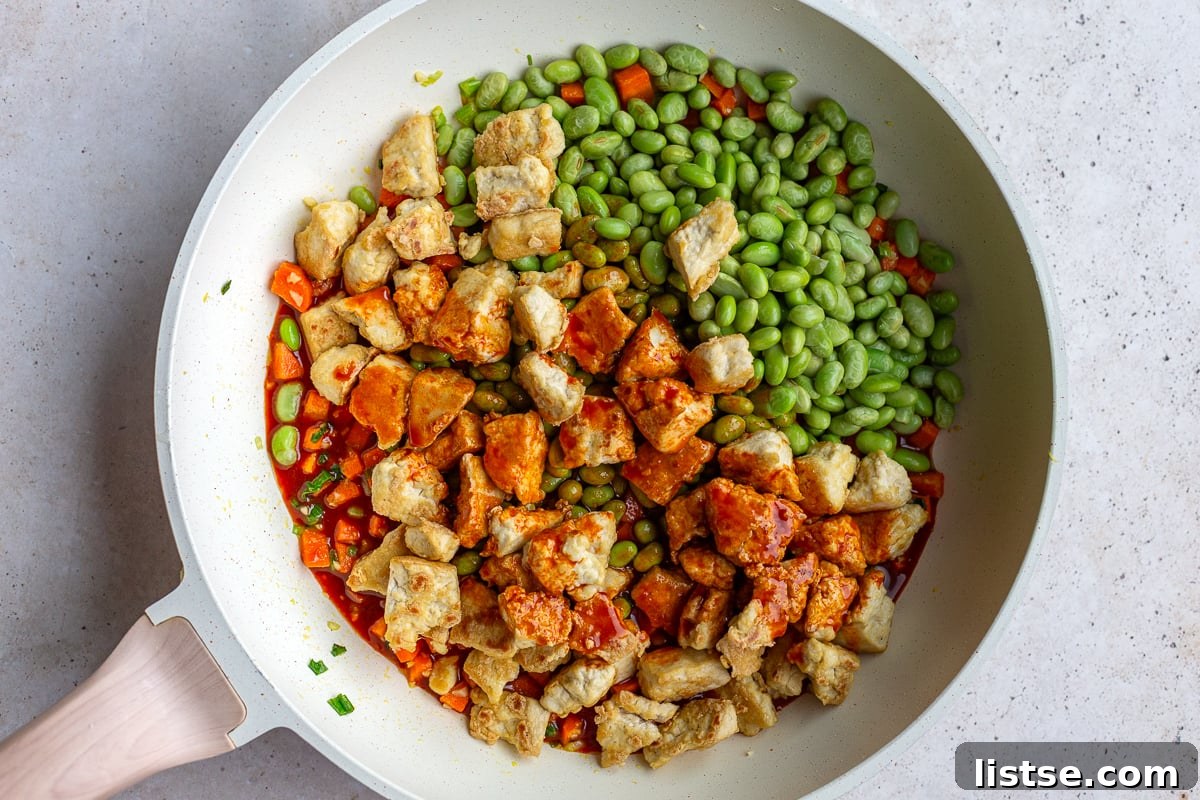 gochujang tofu in a skillet with tofu and edamame on top