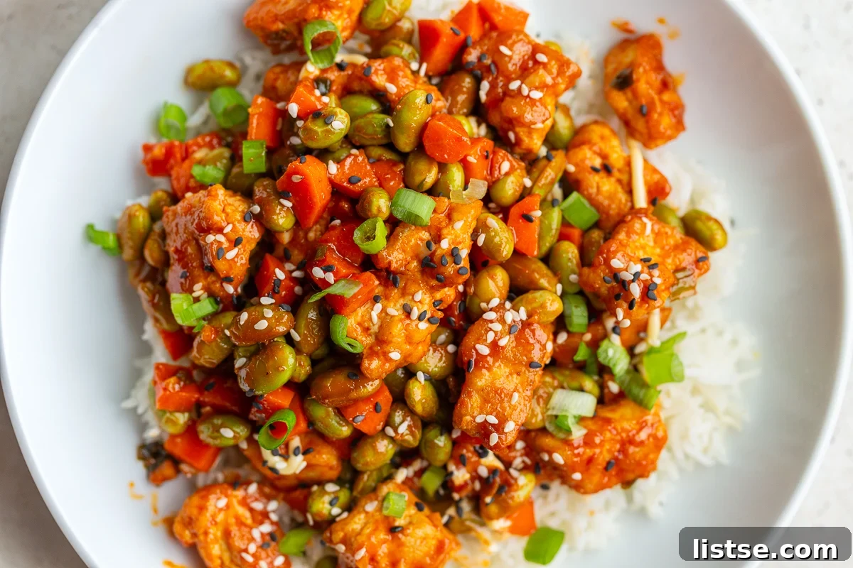 gochujang tofu and edamame stir fry in a large white bowl topped with sesame seeds