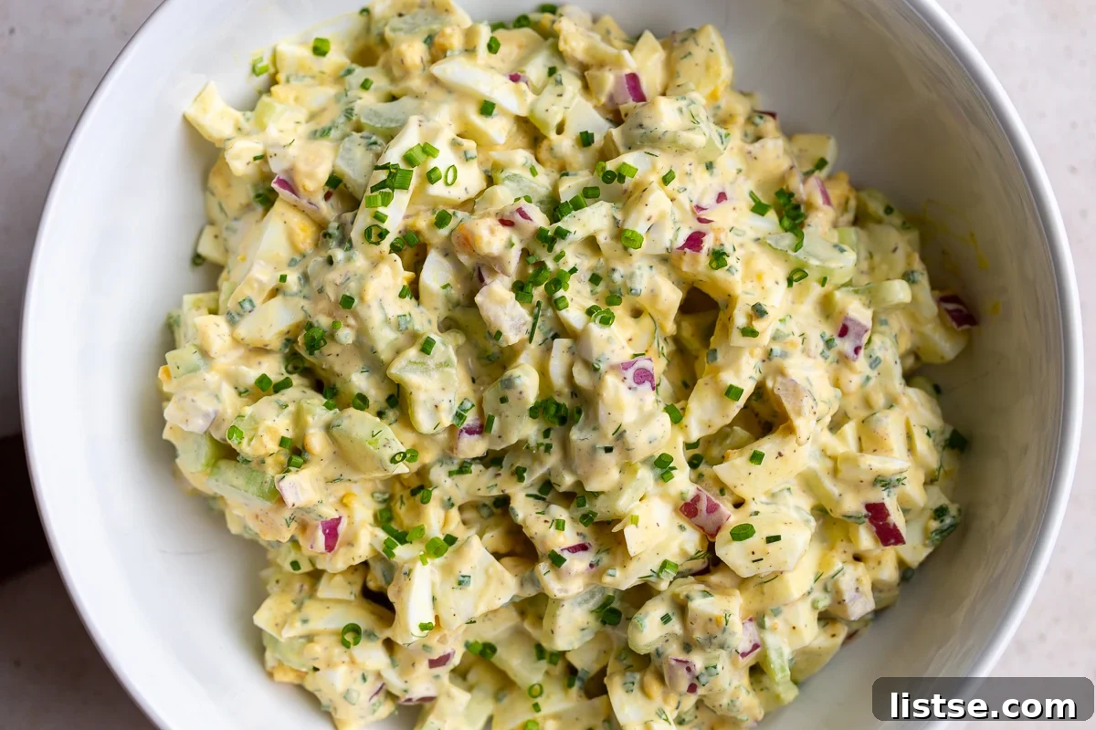 Large bowl filled with homemade egg salad, beautifully topped with fresh chives, ready to be served or enjoyed as a satisfying meal.