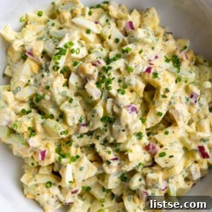 Large bowl filled with homemade egg salad, beautifully topped with fresh chives.