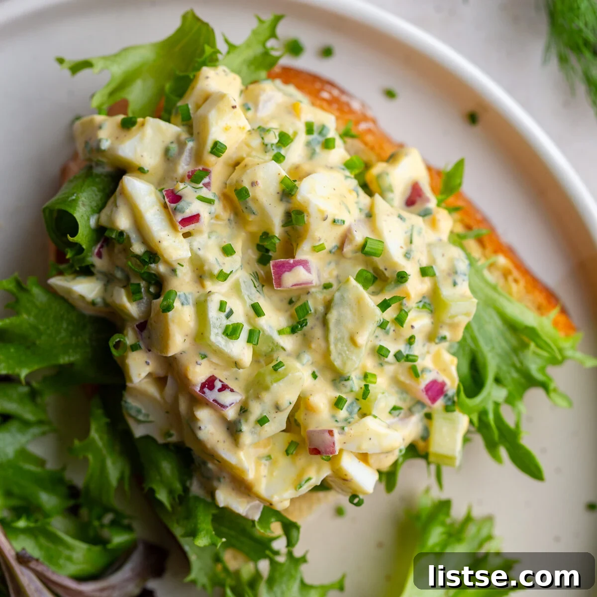 A delicious homemade egg salad sandwich garnished with fresh greens, meticulously cut in half and stacked for easy enjoyment, showcasing the perfect lunchtime treat.