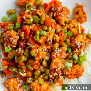 Gochujang tofu and edamame stir fry in a large white bowl topped with sesame seeds - a delicious 30-minute vegetarian dinner