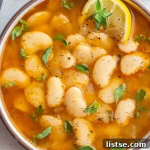 brothy beans in a large bowl with lemon and fresh herbs