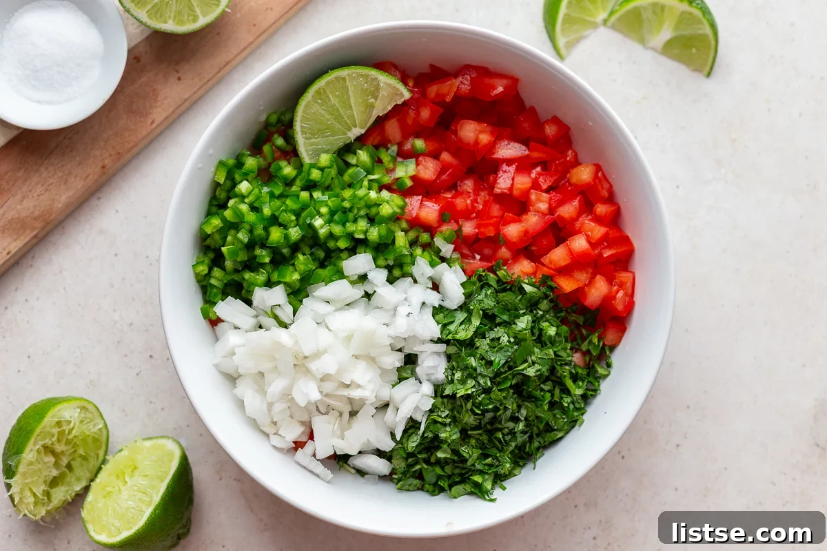 Crafting Perfect Pico de Gallo 7 ingredients for pico de gallo sectioned out in a large bowl including tomatoes, jalapeno, cilantro, onion, and lime