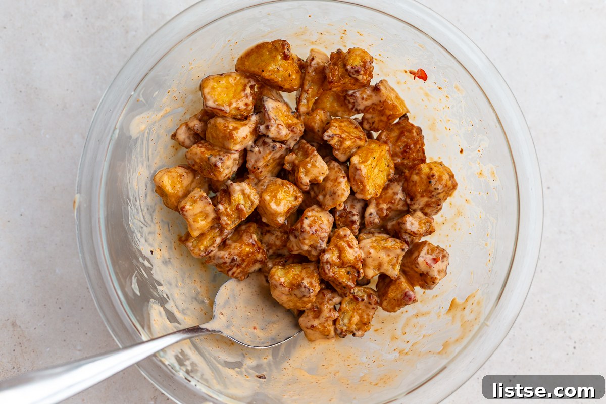 Crispy Bang Bang Tofu: Air Fry or Pan Fry 7 bang bang tofu in a large bowl with a spoon