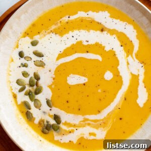 Creamy Roasted Butternut Squash Soup in a large bowl drizzled with cream and pepitas