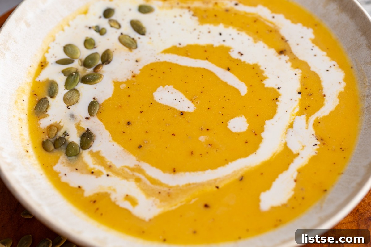 Creamy Roasted Butternut Squash Soup in a large bowl drizzled with cream and pepitas