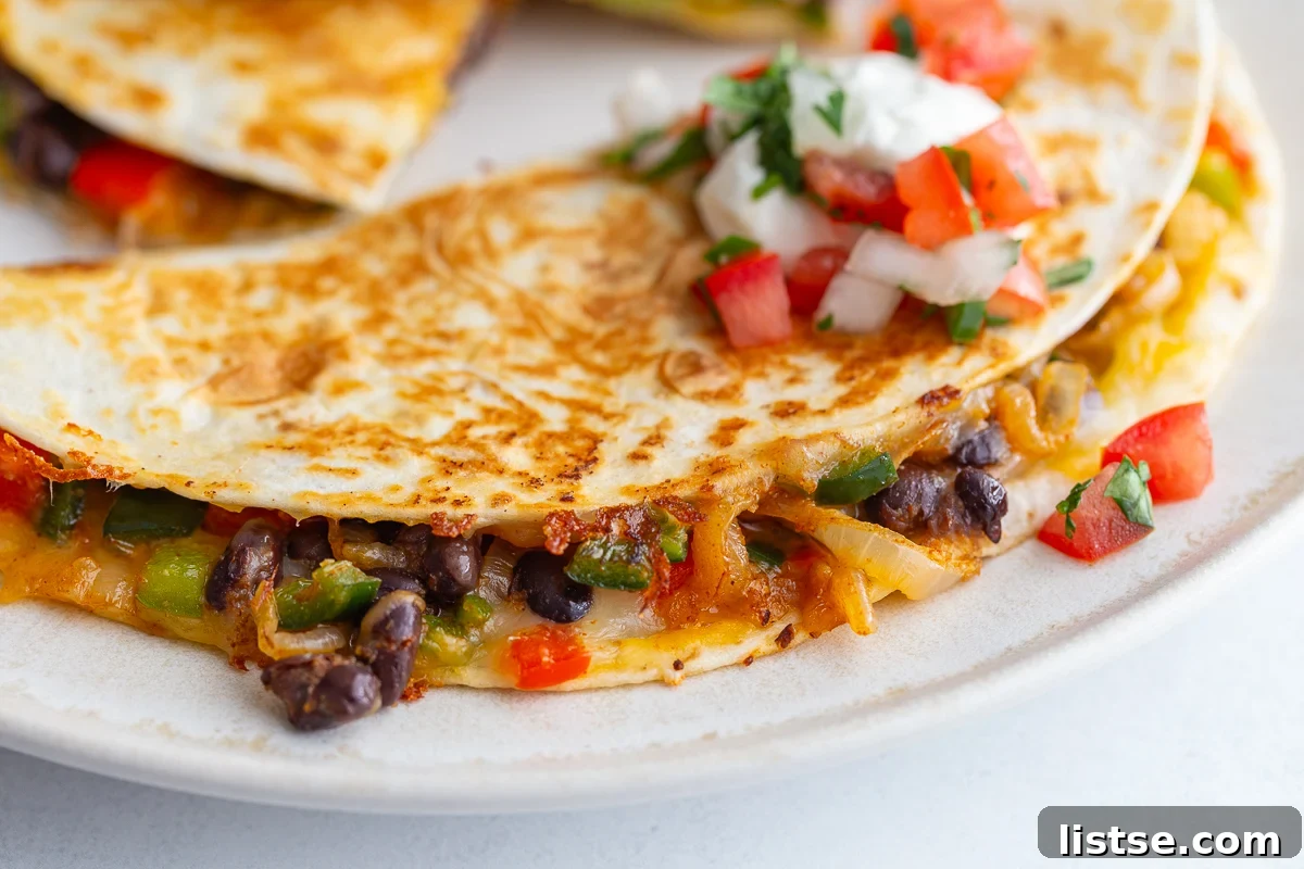 Effortless Meatless Quesadillas 2 Stack of golden brown vegetarian quesadillas filled with colorful bell peppers, caramelized onions, black beans, and melted cheese, garnished with fresh cilantro.