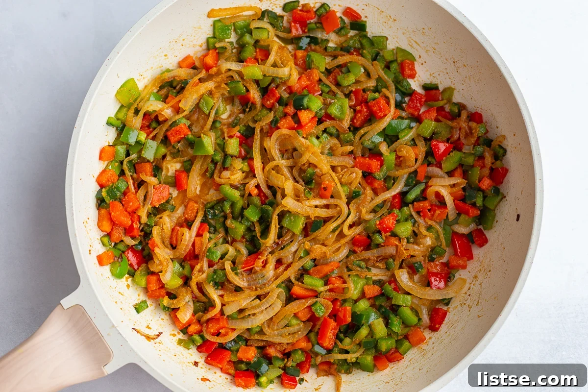Effortless Meatless Quesadillas 5 Sautéed sliced onions and diced bell peppers cooking in a large skillet with black beans.