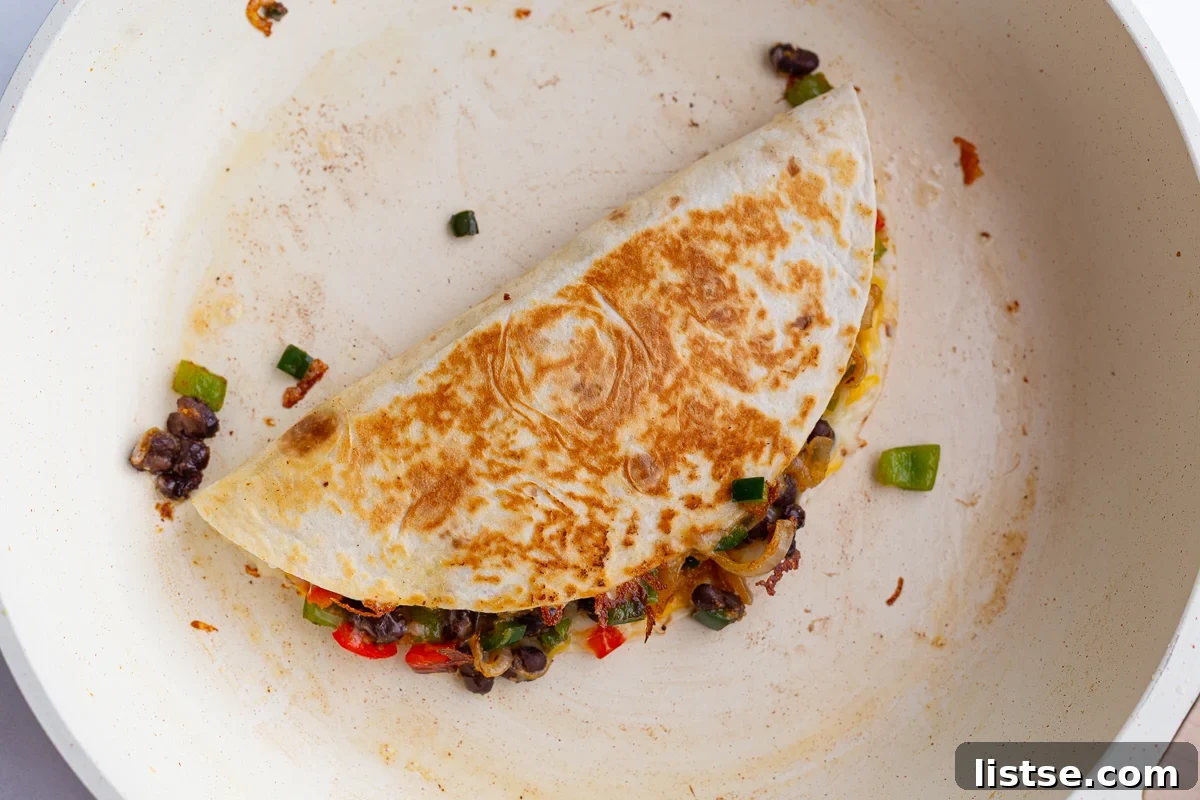 Effortless Meatless Quesadillas 8 A freshly cooked vegetarian quesadilla with a golden-brown tortilla and melted cheese, resting in a large white skillet.