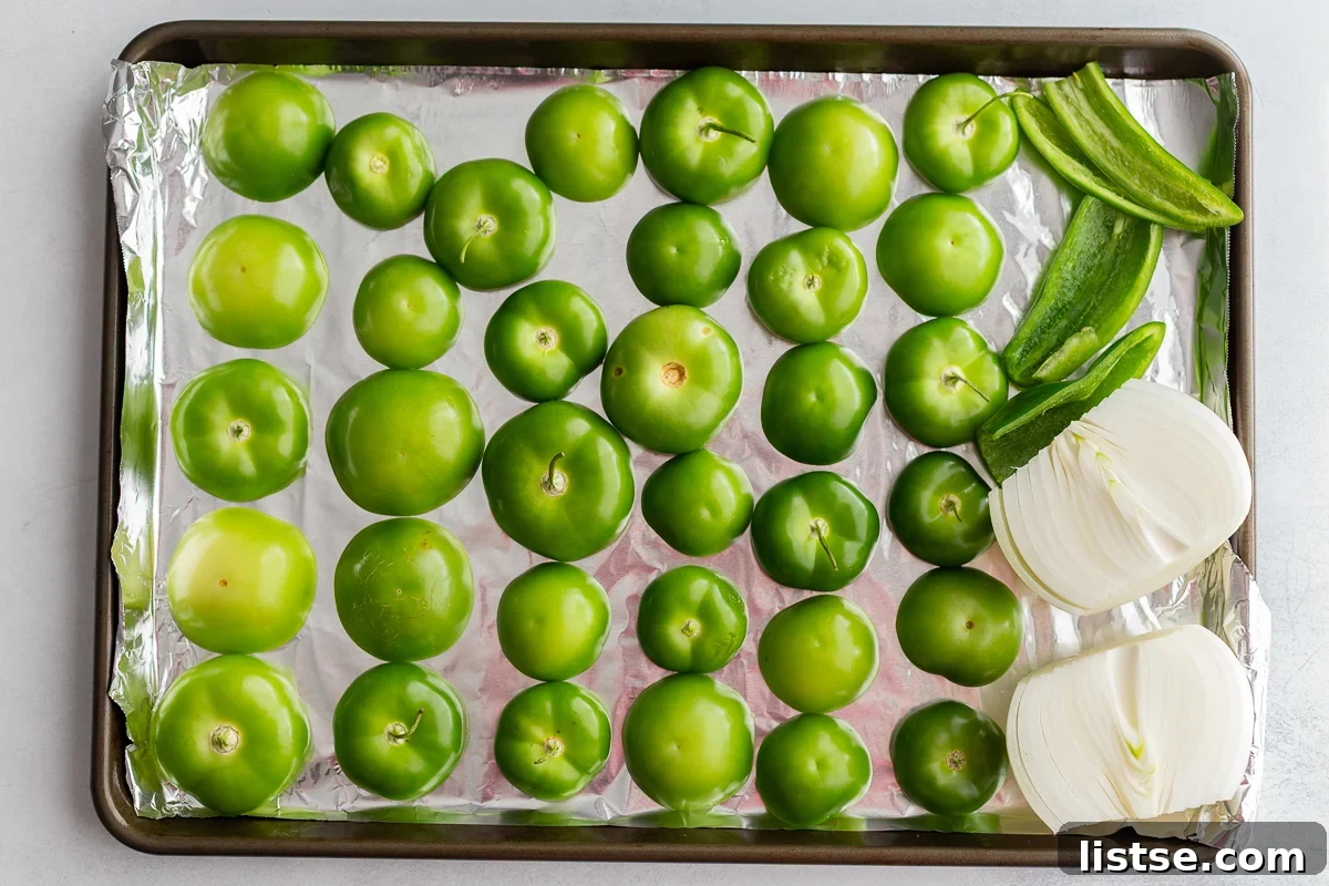 A vibrant close-up of fresh tomatillos and peppers on a baking sheet, lightly charred after roasting, ready for blending into salsa verde.