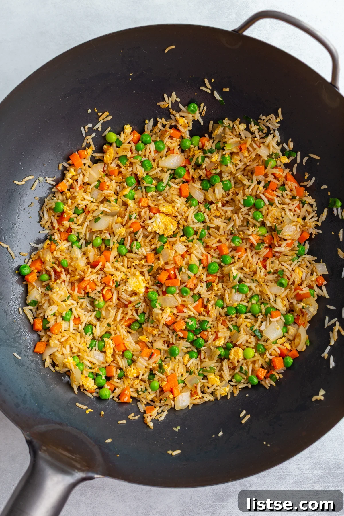 Vegetarian fried rice being vigorously stir-fried in a large, hot wok, illustrating the dynamic motion and steam rising, creating delicious aromas and textures.