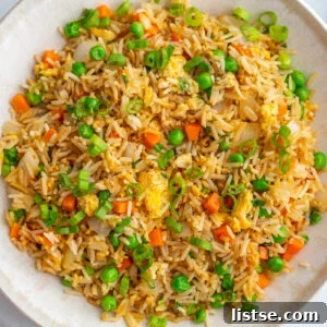 Large white bowl of vegetarian fried rice, garnished with green onions.