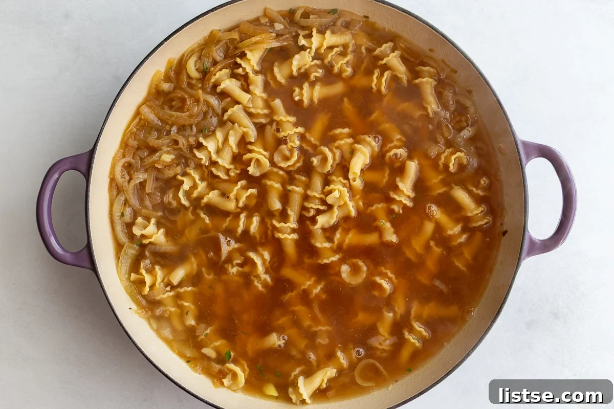 French onion pasta in a pot before the pasta has been fully cooked, submerged in broth