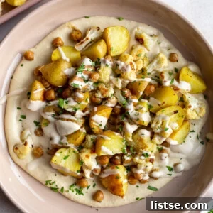 Hearty Roasted Potato, Chickpea, and Cauliflower Bowls, garnished with fresh herbs and a creamy dressing.