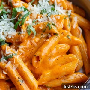 A comforting bowl of roasted red pepper pasta, garnished with fresh herbs.