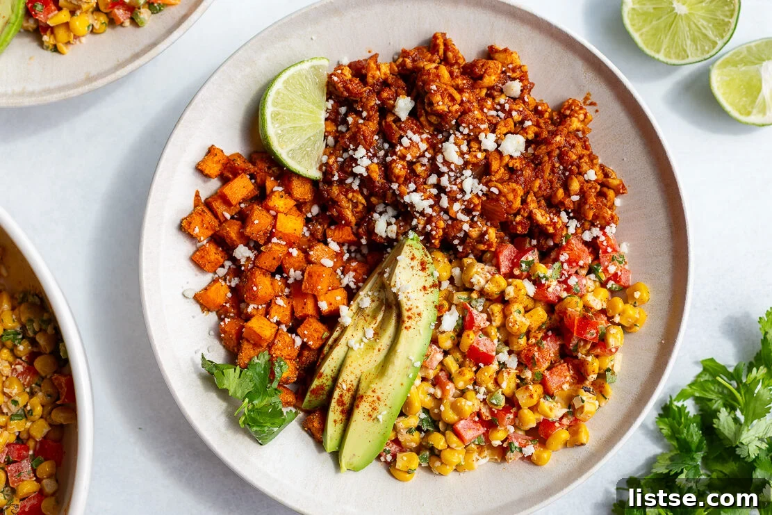 Vegetarian Street Corn Tofu Bowls featuring roasted sweet potato, savory ground tofu "meat", creamy sliced avocado, a fresh lime wedge, and a vibrant Mexican street corn salad, all beautifully arranged in a rustic bowl.