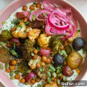 Weekly Culinary Guide 42 5 A pink bowl filled with roasted vegetables like chickpeas, cauliflower, and broccoli served over a bed of creamy tzatziki sauce.
