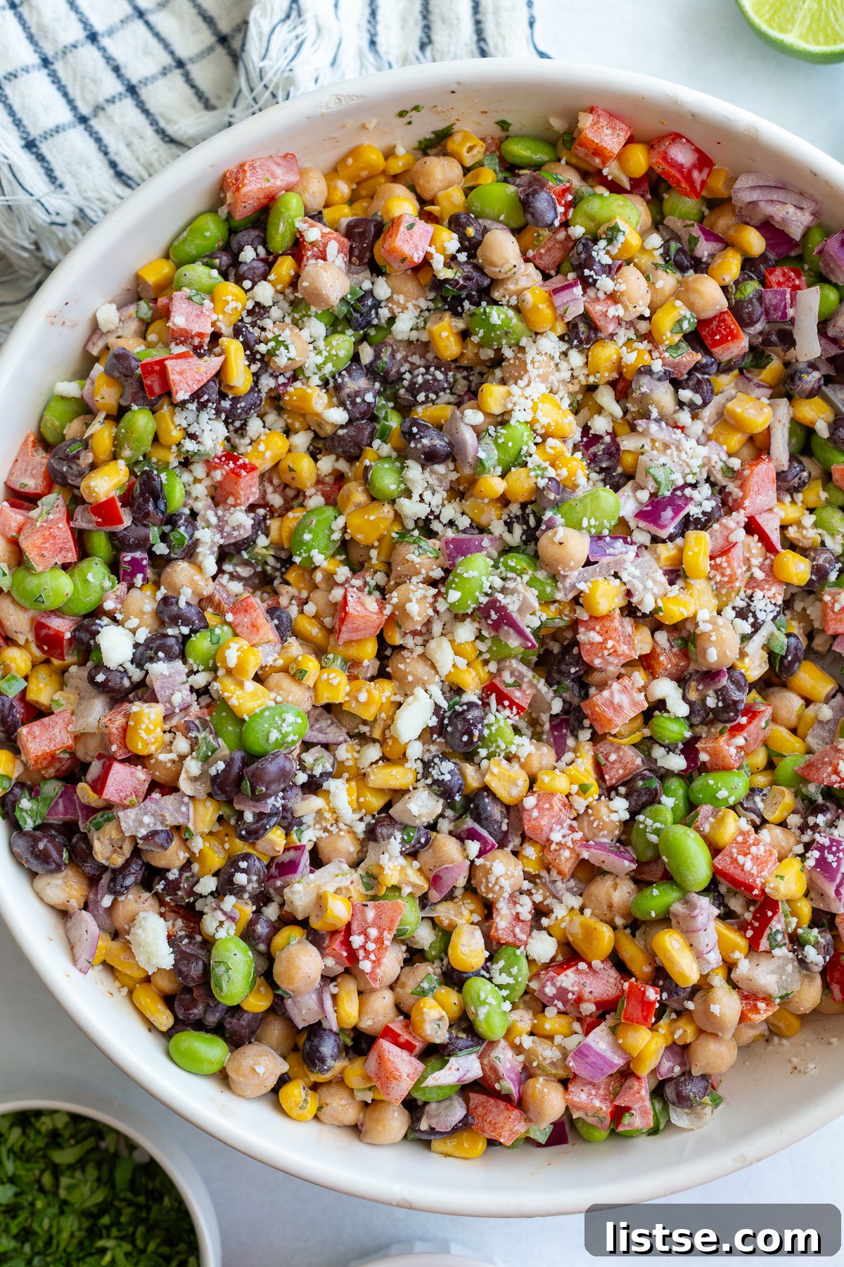 A tall, vertical shot of the finished Mexican street corn bean salad in a bowl, ready to be served.