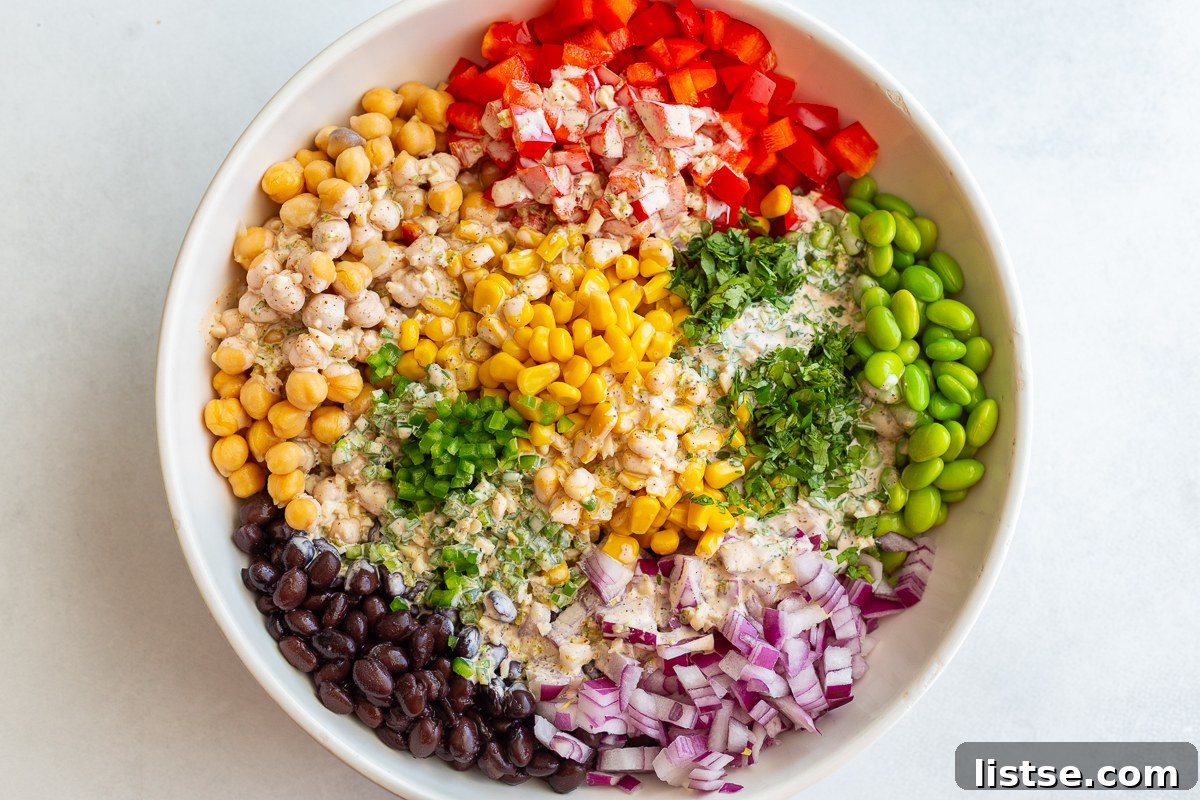 Pouring the creamy dressing over the bowl of mixed beans and vegetables.